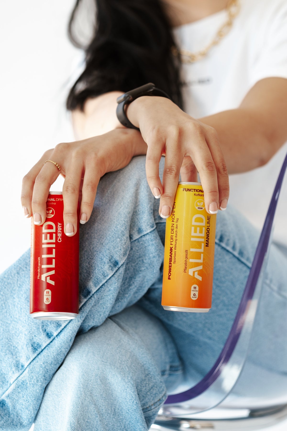 Sitzende Person hält eine gelbe Mango Lime und eine eine rote Cherry Dose.
